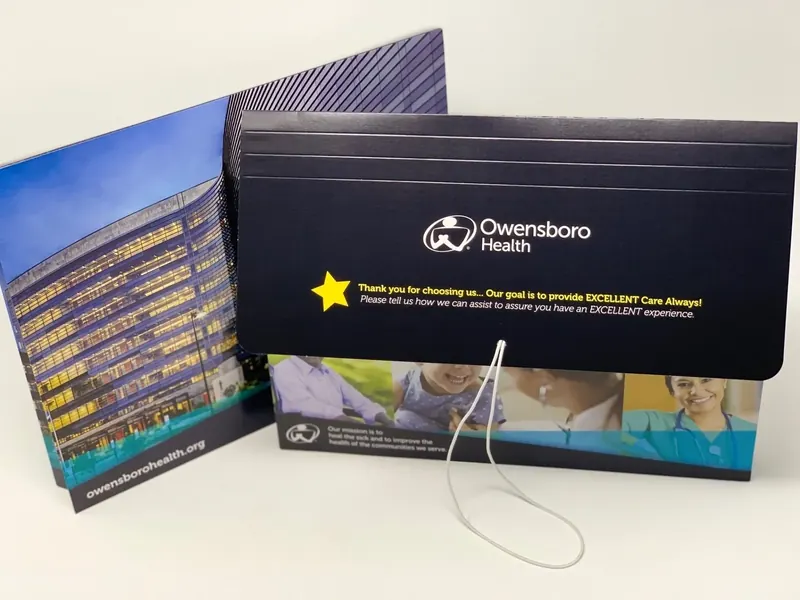 Owensboro Health admit and discharge folder standing open, its cover printed with the hospital tower and a thank-you message