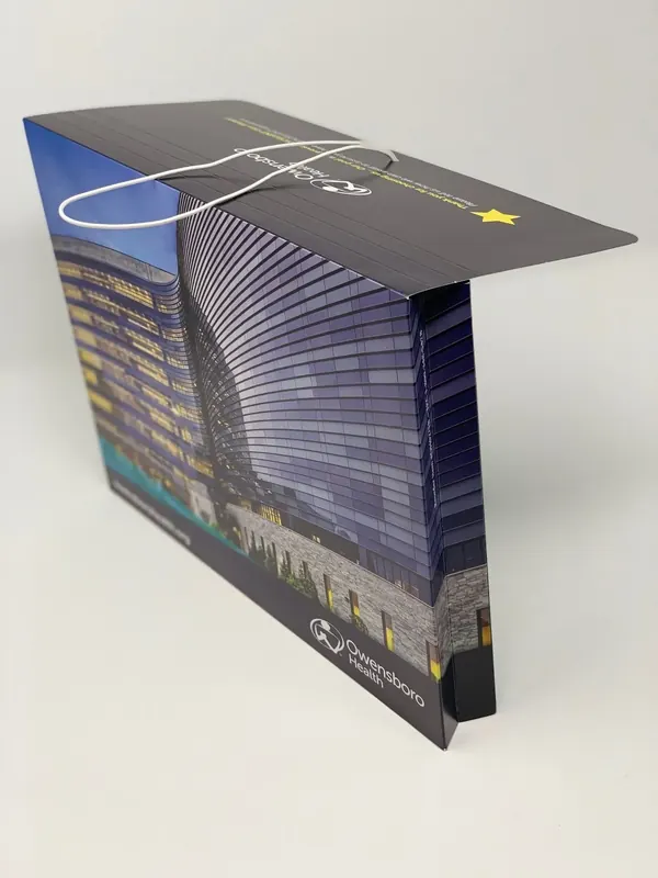 Owensboro Health folder standing upright with the tower artwork wrapping the front panel and spine