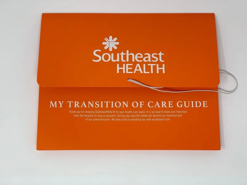 Orange SoutheastHEALTH My Transition of Care Guide folder, closed, with an elastic loop closure